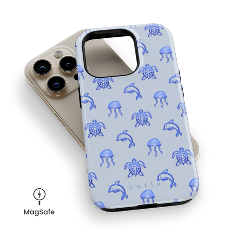 Blue Drift MagSafe phone case featuring glossy blue turtles, dolphins, and jellyfish floating on a cool pale blue background, top down view on iPhone