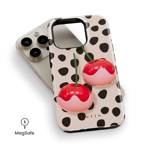 Choco Cherries MagSafe phone case featuring charming 3D-look white chocolate-covered red cherries set against black dots pattern on a soft beige background, top down view on iPhone