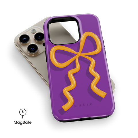 Present Moment - Purple MagSafe phone case featuring a glossy orange bow design on a rich purple background, resembling a gift wrap ribbon, top down view on iPhone