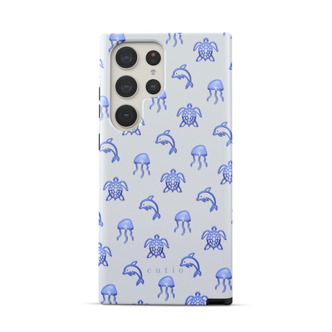 Blue Drift tough phone case featuring glossy blue turtles, dolphins, and jellyfish floating on a cool pale blue background, front view on Samsung Galaxy phone