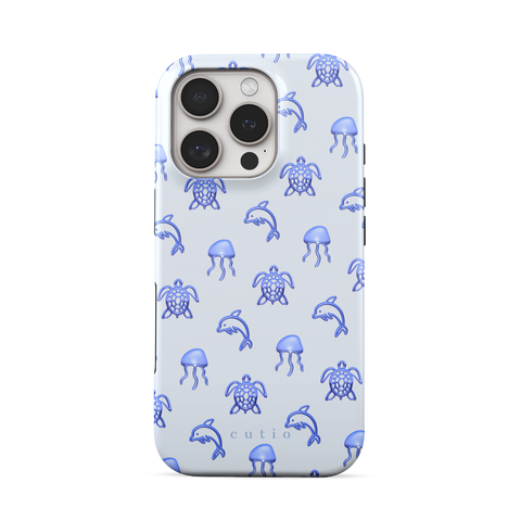 Blue Drift tough phone case featuring glossy blue turtles, dolphins, and jellyfish floating on a cool pale blue background, front view on iPhone