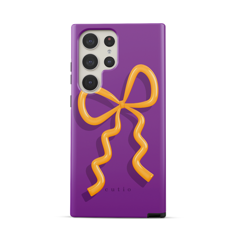 Present Moment - Purple tough phone case featuring a glossy orange bow design on a rich purple background, resembling a gift wrap ribbon, front view on Samsung Galaxy phone